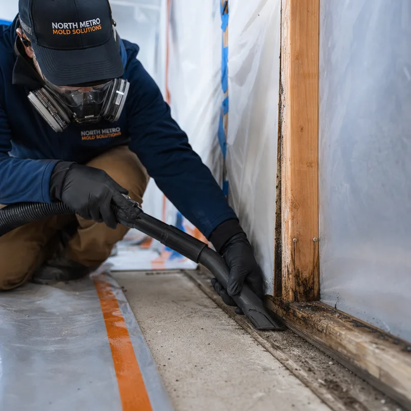 HEPA vacuuming exposed studs and a sill plate inside containment